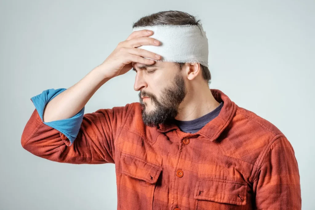 A man with his head wrapped and he's holding it after a brain injury.