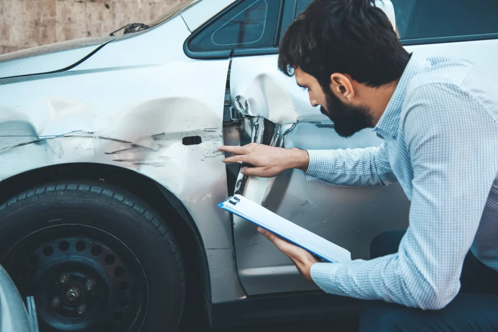 An insurance adjuster looking at a damaged car.