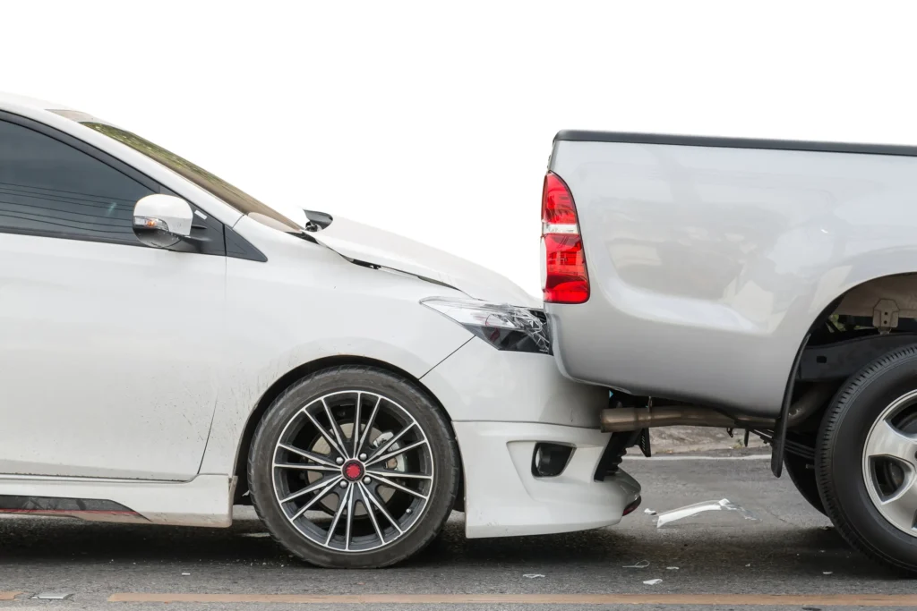 A white car hitting the back of a truck.