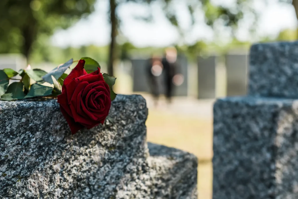A red rose laid on a tombstone.