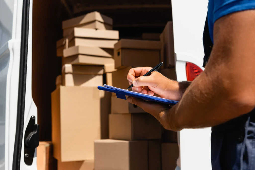 Salt Lake City delivery worker inspecting cargo and checking a clipboard next to a commercial delivery vehicle loaded with boxes, highlighting delivery truck accident risks.