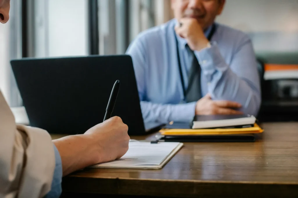 A person takes notes while speaking with a professional in an office setting, representing a consultation with an Arizona wrongful death attorney.